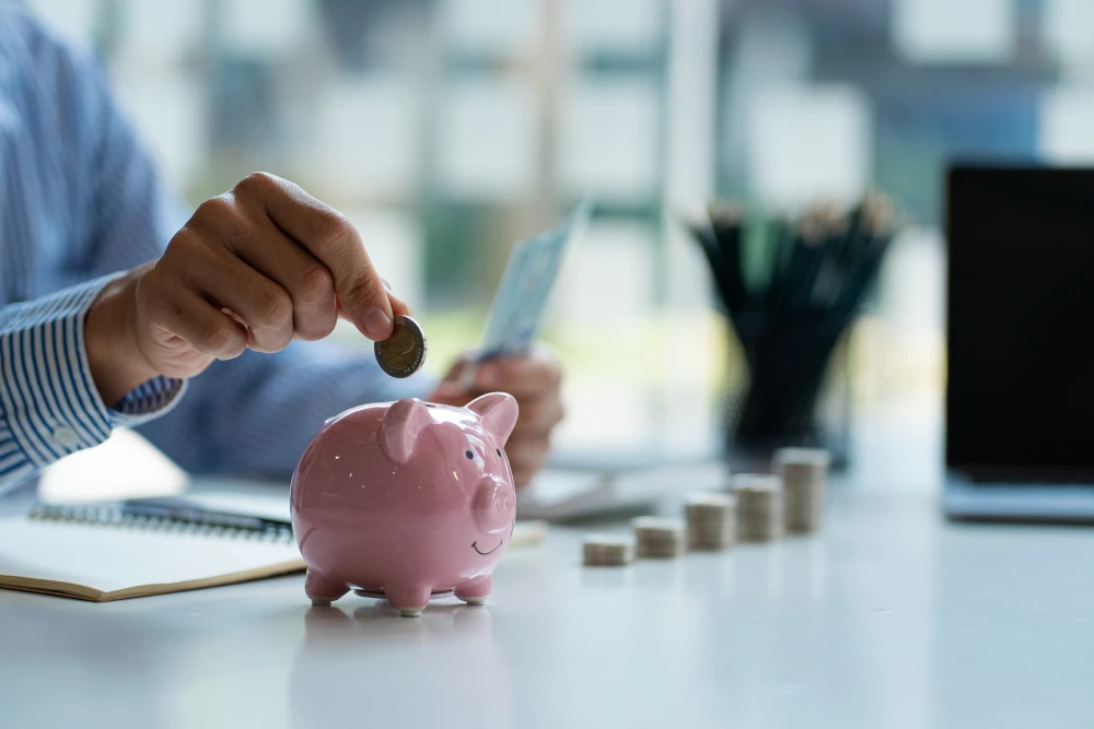 Hand putting money into a small piggy bank
