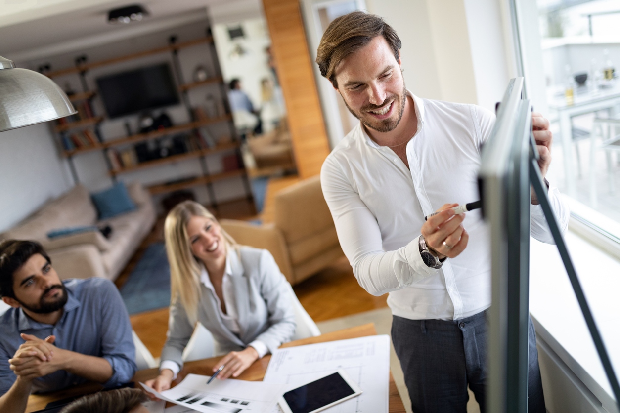 business man stood at board talking to his team