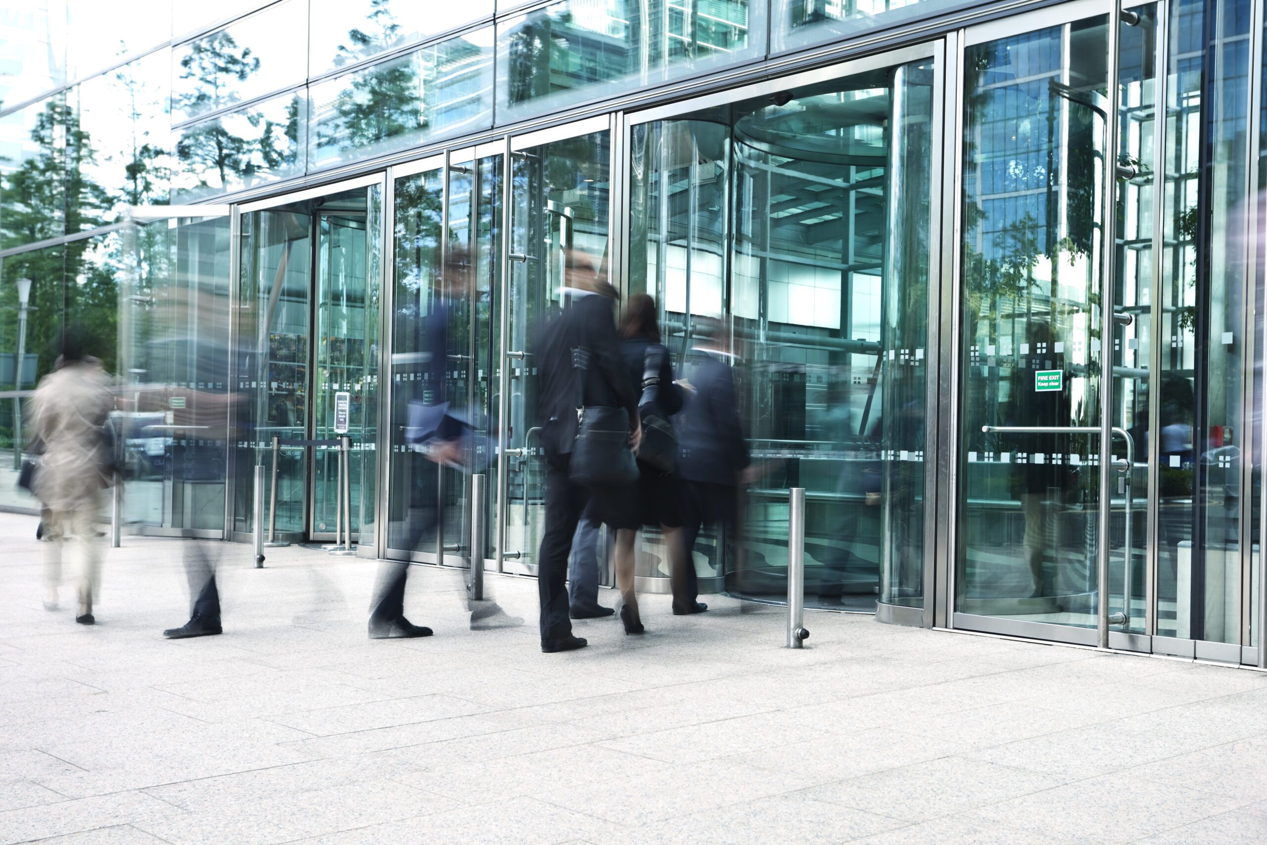 Business people entering office building through revolving doors